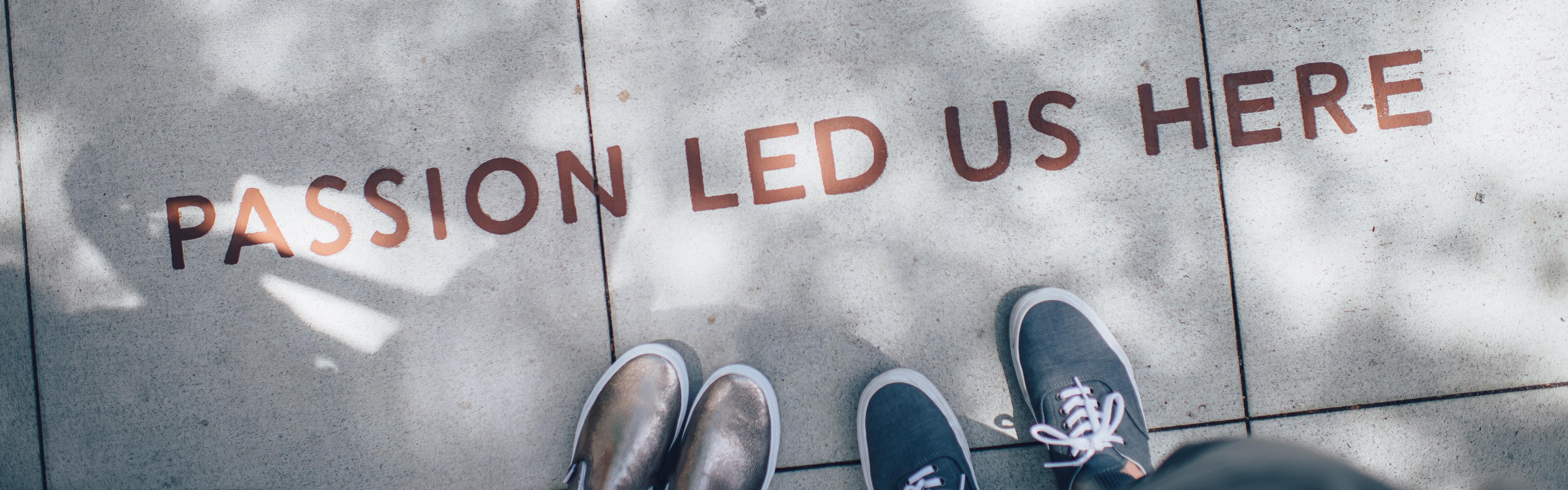 Photograph of two people's feet and concrete floor with slogan 'Passion led us here'